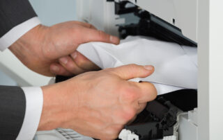 man pulling jammed paper out of copier in need ofcopy machine repair in Las Vegas